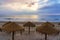 Tropical umbrellas on the sandy beach at sunset with a calm sea.