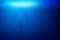 Tropical underwater dark blue deep ocean wide nature background with rays of sunlight.