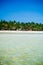 Tropical white sand beach with green palm trees and parked fishing boats in the sand. Exotic island paradise