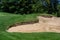 Trouble on the golf course, sand trap protecting a golf green with trees in the background