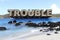 TROUBLE in PARADISE - Large Text Protrudes from Island