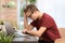 Troubled teenage boy with laptop at table