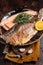 Trout roasted fillet, grilled fish on a plate with thyme and lemon. Dark background. Top view