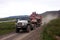 Truck carries all-terrain tracked vehicle at gravel road tundra