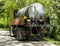 A truck with a cistern for transporting tar or bitumen on the side of a road in a public park. Repair of asphalt roads. Asphalt