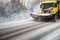 Truck cleaning on winter road covered with snow