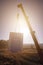 A truck crane raises white blocks to the construction site against the background of the sun shining