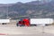 Truck driver repairing broken red big rig semi truck on the truck stop amid high mountains in Utah