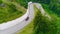 Truck drives along serpentine road. Scene. Top view of truck driving along serpentine uphill on background of green