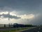 A truck is driving along the asphalt road in perspective. Cloudy rainy sky above him