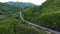 Truck driving on the asphalt road in a rural landscape with forested mountains in the background aerial view