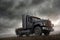 A truck is driving on the ground. Dark dramatic landscape with forest as background, gloomy sky, rainy clouds. Generative AI