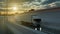 Truck driving on a highway at sunset backlit by a bright orange sunburst under an ominous cloudy sky. Transports, logistics