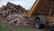 Truck emptying its dumpster of rubbish, rubble in nature