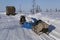 Truck with hay and a snowmobile with cargo on winter road.