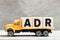 Truck hold block in word ADR Abbreviation of Adverse drug reaction on wood background