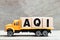 Truck hold block in word AQI Air quality index on wood background