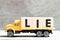 Truck hold block in word lie on wood background