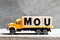 Truck hold block in word MOU Abbreviation of memorandum of understanding on wood background