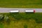 Truck logistic aerial. Two trucks motion by the road between fields. View from drone