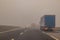 Truck or lorries and one van overtaking at a dangerous time with thick fog on a motorway in italy, europe