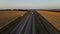 truck moves along the highway among the wheat fields at sunset