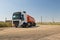 A truck with an orange tank goes on a knurled unpaved road