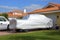 Truck with a protective cover in driveway of a modest house with an orange tile roof