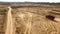 Truck rides on sand quarry road. Scene. Top view of dump truck driving on yellow dirt road in countryside. Large trucks