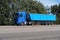 Truck on the road, side view, empty space on a blue container - concept of cargo transportation, trucking industry