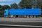 Truck on the road, side view, empty space on a blue container - concept of cargo transportation, trucking industry
