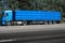 Truck on the road, side view, empty space on a blue container - concept of cargo transportation, trucking industry