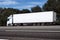 Truck on the road, side view, empty space on a white container - concept of cargo transportation, trucking industry