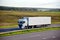 Truck with semi-trailer driving along highway on the sunset background. Goods delivery by roads. Services and Transport logistics