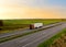 Truck with semi-trailer driving along highway on the sunset background. Goods delivery by roads. Services and Transport logistics