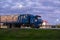 Truck with semitrailer moves along a road past gas station