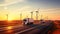 A truck speeds in front of wind turbines on a highway at sunset