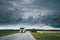 Truck, Tractor Unit, Prime Mover, Traction Unit In Motion On Country Road, Freeway In Europe. Cloudy Sky Above The