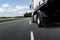 A truck with trailer moves fast along a road