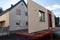 Truck trailer in orange in front of a prefabricated house including a gray front door for a prefabricated house
