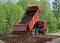 A truck unloads sand on a country road to level and repair the pavement