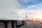 Truck with a white trailer drives along the highway in heavy traffic in the evening at sunset