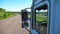 Trucker in sunglasses reflecting in side mirror of moving car. Man driving lorry riding to destination through