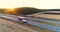 Trucks drive along the highway among the fields at sunset. Trucks travel on a straight road at sunset top view