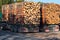 Trucks loaded with tree trunks along the roadside in front of a