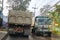 Trucks pass by in a narrow street