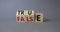 True vs False symbol. Wooden cubes with words False and True. Beautiful grey background. Business and True vs False concept. Copy