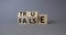 True vs False symbol. Wooden cubes with words False and True. Beautiful grey background. Business and True vs False concept. Copy