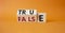 True vs False symbol. Wooden cubes with words False and True. Beautiful orange background. Business and True vs False concept.