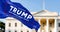 Trump flag waving with blurred White House in the background